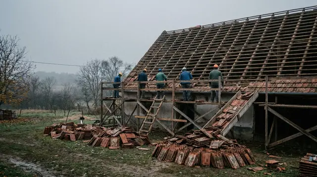 Tetőcsere közben a régi cserepeket lebontották, a csupasz szarufákon állványról dolgoznak, előtérben cserépkötegek